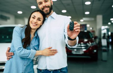 Mutlu çifte sarılma ve anahtar ayakta araba bayilik arka planda gösterilen