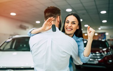 Kucaklama içinde Bayilik, arabanın anahtarını gösterilen kadın ayakta mutlu genç çift 