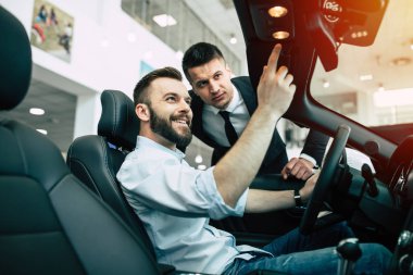 Sakallı adam yeni cabriolet galerisinde, onu ayrıntıları gösteren satıcı satın alma