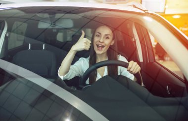 Kendine güvenen güzel kadın yeni modern araba gösteren başparmak yukarı sürüş