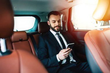 Arabada oturan smartphone kullanarak emin yakışıklı işadamı
