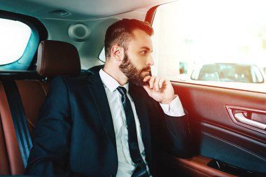 Arabanın içinde otururken kendine güvenen düşünceli işadamı