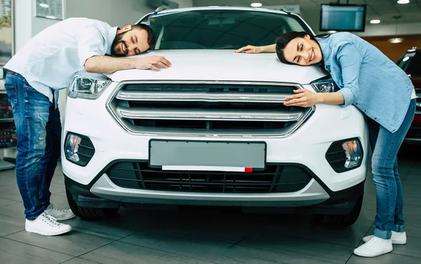 Rahat mutlu genç çift yeni araba sarılma başlık içinde araba konsepti satın alma Bayilik, giymek.