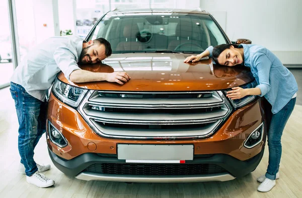 Rahat mutlu genç çift yeni araba sarılma başlık içinde araba konsepti satın alma Bayilik, giymek.