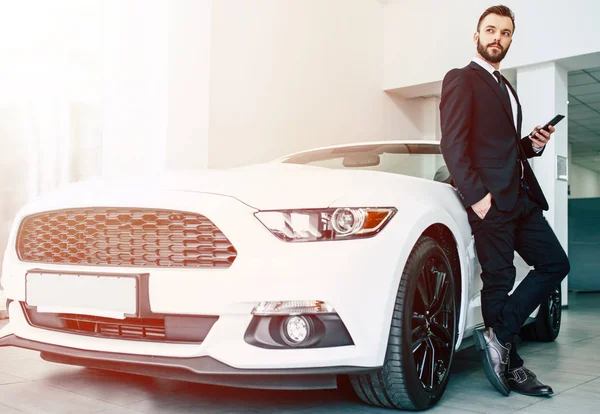 siyah elbiseli Bayilik, tam uzunlukta yeni modern car yakınındaki smartphone ayakta tutan yakışıklı adam
