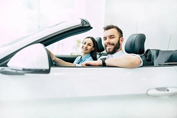 Feliz Jovem Casal Sentado Novo Carro Branco Concessionária Vista Lateral — Fotografia de Stock