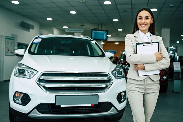 Takım elbise ayakta Bayilik araba arka plan üzerinde belgeleri ile güzel gülümseyen pazarlamacı