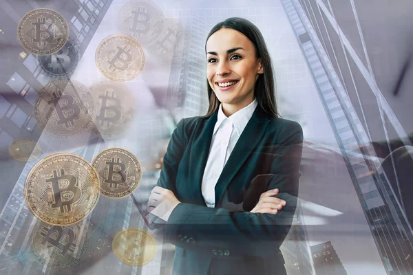 Bitcoin の兆候とオフィス背景に交差した腕を持つスーツで美しい笑顔実業家 — ストック写真