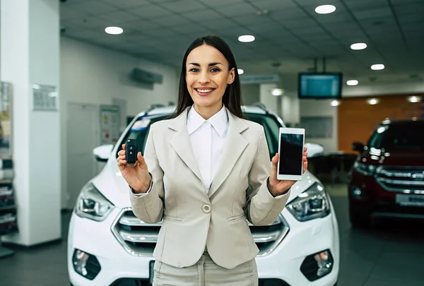 Hermosa Vendedora Sonriente Traje Con Llaves Coche Teléfono Inteligente Manos —  Fotos de Stock