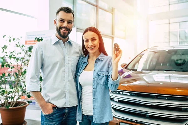 Mutlu çifte sarılma ve anahtar ayakta araba bayilik arka planda gösterilen