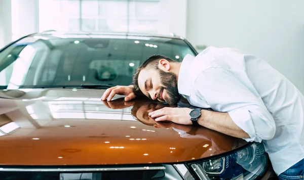 yeni arabanın kaputuna içinde Bayilik sarılma mutlu gülümseyen adam