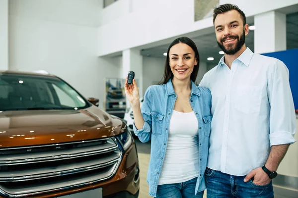 Happy Couple Hugging Showing Key Standing Car Background Dealership — Stock Photo, Image
