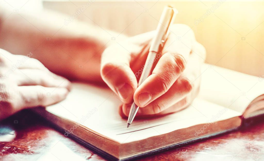 male hand is writing in  notepad 