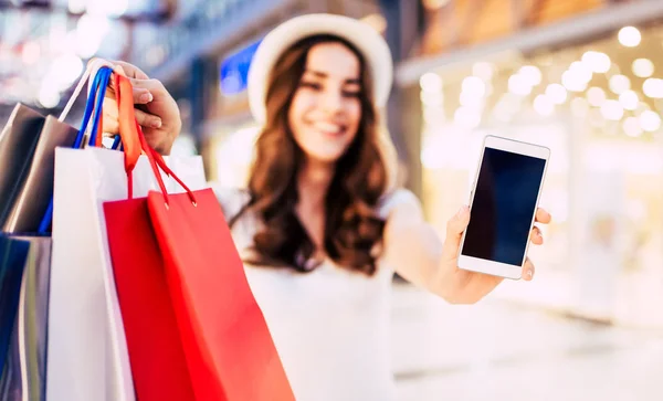 Mujer con bolsas mostrando el teléfono —  Fotos de Stock