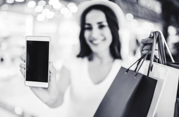 Woman with bags showing phone — Stock Photo, Image