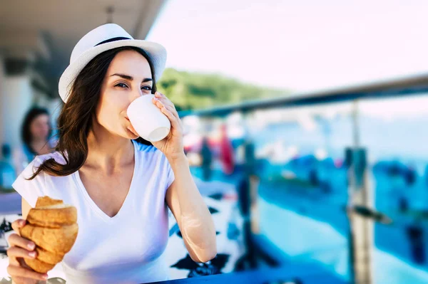 Donna mangiare croissant e bere caffè — Foto Stock