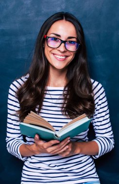 Genç kadın kitap kara tahta arka plan ile poz