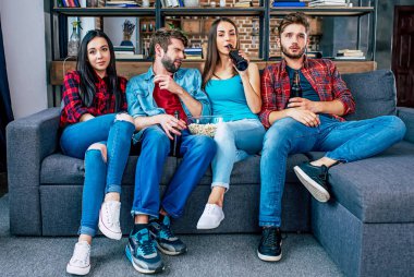 Bira içip patlamış mısır yeme oturma odasında genç arkadaş grubu 