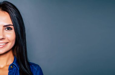 Gri arka plan üzerinde gülümseyen genç esmer kadın portresi kırpılmış