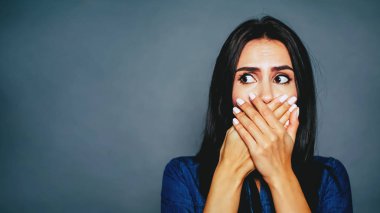 Genç kadın ağız eller tarafından gri arka plan üzerinde kapanış.