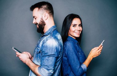 Genç çift akıllı telefonlar üzerinde gri arka plan kullanarak