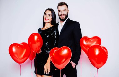 Genç çift beyaz arka plan üzerinde kırmızı balonlarla poz