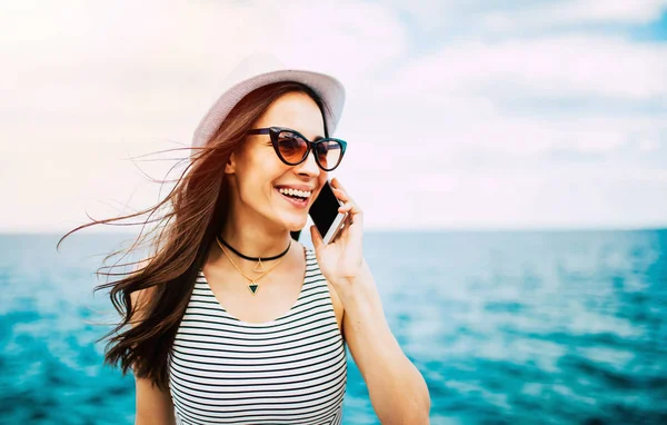 海洋の背景にスマート フォンで話している若い笑顔の女性 — ストック写真