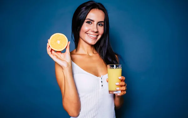 Smiling woman posing with glass of orange juice on blue background