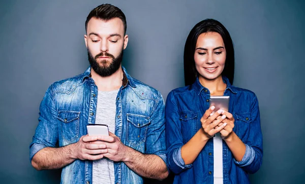 Genç çift akıllı telefonlar üzerinde gri arka plan kullanarak