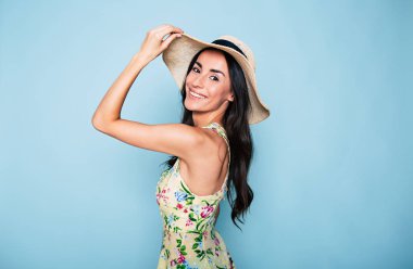 Genç esmer kadın mavi arka plan üzerinde poz şapkalı