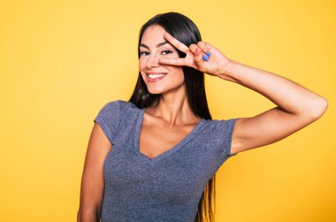 Esmer gösteren barış işareti sarı arka plan üzerinde gülümseyen portresi