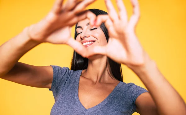 Mladá Bruneta Žena Ukazuje Znamení Srdce Žlutém Podkladu — Stock fotografie