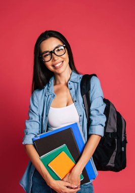 Genç esmer kırmızı zemin üzerine not defterleri ile poz portresi 