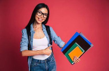 Genç esmer kırmızı zemin üzerine not defterleri ile poz portresi 