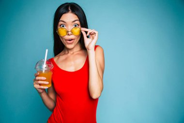 Mavi arka plan üzerinde taze tutan gözlüklü genç esmer portresi 