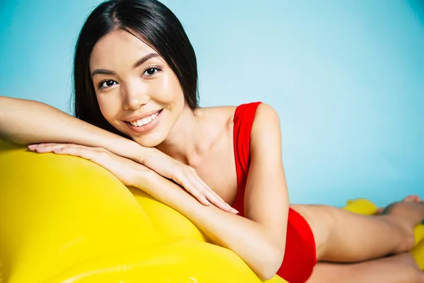 Junge Asiatin Liegt Auf Gelber Luftmatratze Auf Blauem Hintergrund — Stockfoto
