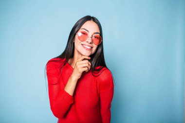 Mavi arka plan üzerinde poz güneş gözlüğü şık esmer portresi