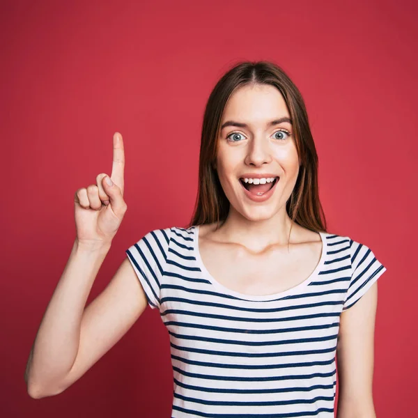 beautiful happy brunette woman pointing on red background