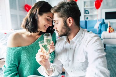 Genç adam ve kadın yatak şampanya içiyor
