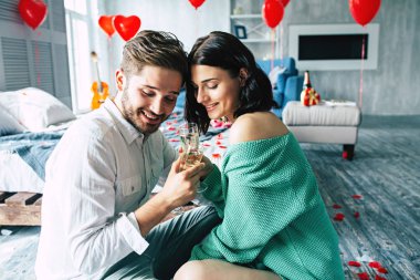 Genç adam ve kadın yatak şampanya içiyor