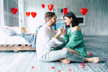 Genç adam ve kadın yatak şampanya içiyor