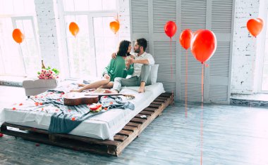 Genç adam ve kadın yatakta şampanya içmek