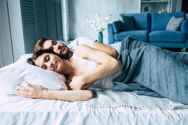 Genç heteroseksüel çift yatağa sarılma