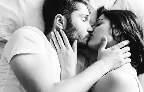 Genç heteroseksüel çift yatakta öpüşme