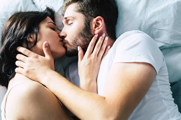 Young heterosexual couple kissing on bed