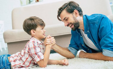 Genç gülümseyen baba oğluyla evde oynarken