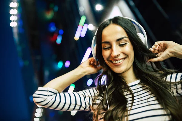 Young smiling woman listening to music in headphones with smartphone