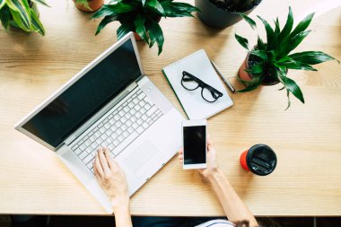 Dizüstü bilgisayarda çalışan ve şık kafe smartphone kullanarak genç casual kadın