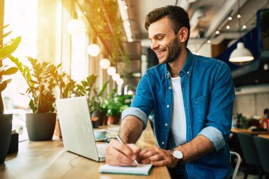 kafede dizüstü bilgisayarda çalışırken notları yapma genç adam 