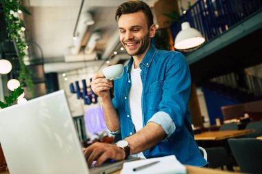 molası verdikten ve kafede dizüstü bilgisayarda çalışırken kahve içme genç adam